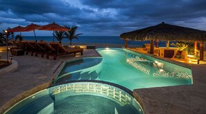A pool area with lounge chairs and umbrellas, a thatched-roof structure, and a view of the ocean. - The Ultimate Holiday Villa in Cabo San Lucas With Private Pool and Close to the Beach, Cabo San Lucas Villa 1002 (Cabo San Lucas)