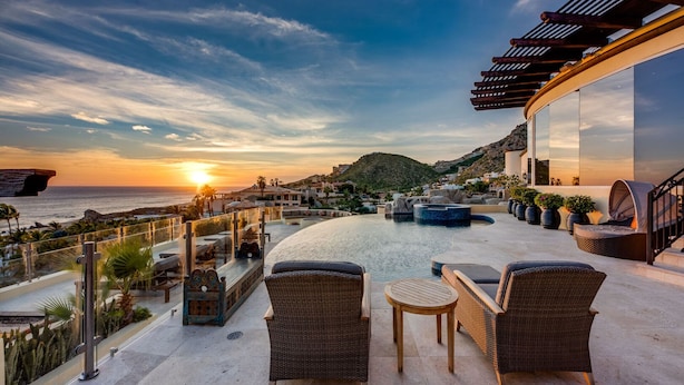 A rooftop terrace with wicker furniture, a pool, and a view of the sunset over the ocean. - The Ultimate Holiday Villa in Cabo San Lucas With Private Pool and Close to the Beach, Cabo San Lucas Villa 1011 (Cabo San Lucas)