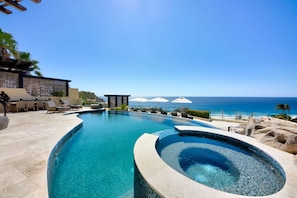 A pool with a view of the ocean, lounge chairs, and umbrellas. - The Ultimate Holiday Villa in Cabo San Lucas With Private Pool and Close to the Beach, Cabo San Lucas Villa 1011 (Cabo San Lucas)