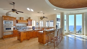 A spacious kitchen with wooden cabinets, a large island, and a view of the ocean. - The Ultimate Holiday Villa in Cabo San Lucas With Private Pool and Close to the Beach, Cabo San Lucas Villa 1011 (Cabo San Lucas)