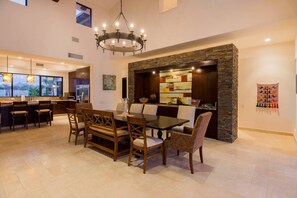 Un comedor espacioso con una pared de acento de piedra, una araña y vistas a la cocina.