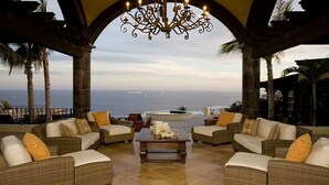 Um terraço com mobiliário de vime, uma mesa de centro e vista para o oceano.