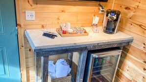 A kitchenette with a coffee maker, a microwave, a small refrigerator, and a wooden table with various items on it. - The Man o' War at Jayell Ranch (Sevier County)