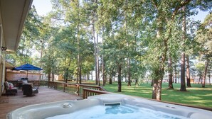 A hot tub on a wooden deck with a view of a grassy area and trees. - *Waterfront* charming cabin w/ private boat dock (Bullard)