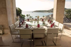 A dining table set for six with white chairs, a glass table, and red napkins.