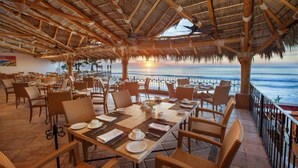 An outdoor dining area with tables and chairs, a thatched roof, and a view of the ocean. - The Ultimate Holiday Villa in San José del Cabo With Private Pool and Close to the Beach, San Jose Del Cabo Villa 1008 (San José del Cabo)