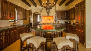 A spacious kitchen with dark wooden cabinets, a central island with stools, and a chandelier. - Luxury Holiday Villa near Main Attractions, San Jose del Cabo Villa 1019 (San José del Cabo)