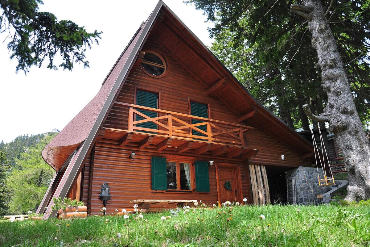 Eine Holzhütte mit einem Giebeldach, einem Balkon und einer Steinmauer.