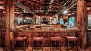 A spacious kitchen with a large island, wooden bar stools, and a rustic interior. - Historic Ranch Lodge + 3 Private Suites Overlooking the Brazos River (Mineral Wells)