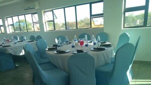 A conference room with round tables, blue chairs, and water bottles.