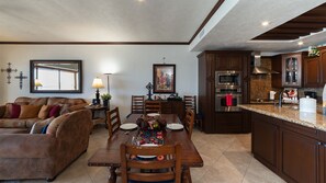 A well-lit living room with a sofa, dining table, and kitchen area with modern appliances. - Sonoran Sky 708 A Wave From It All Charming Oceanfront (Puerto Peñasco)