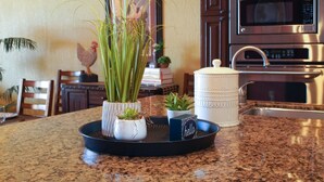 A kitchen counter with a black tray holding a white pot with green plants, a small succulent, and a decorative item with the word "hello". - Sonoran Sky 708 A Wave From It All Charming Oceanfront (Puerto Peñasco)