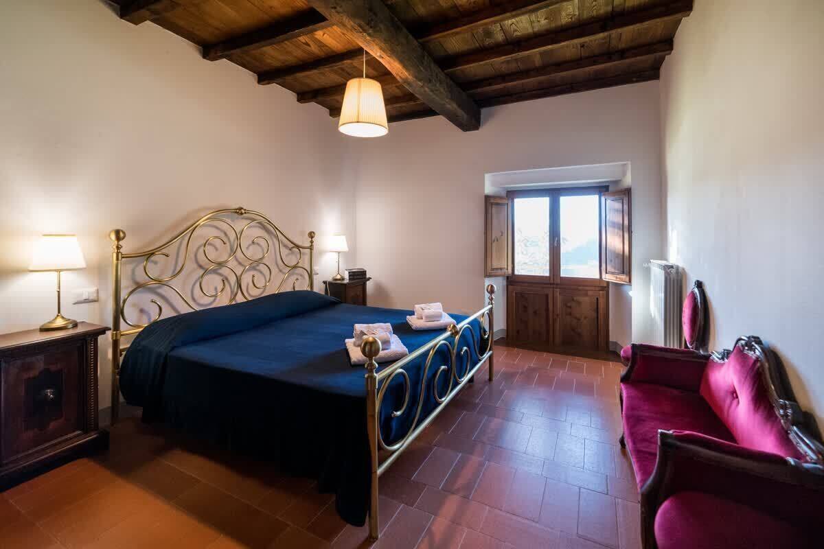 Une chambre à coucher avec un lit, des lampes de chevet, une fenêtre et un fauteuil rouge.