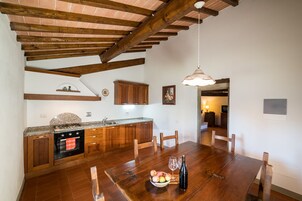 A kitchen with wooden cabinets, a granite countertop, and a dining table with chairs.