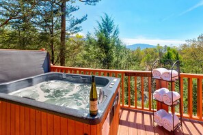A hot tub on a wooden deck with a mountain view, a bottle of wine, and towels on a rack. - Mountain Laurel Log Cabin!!! (Gatlinburg)