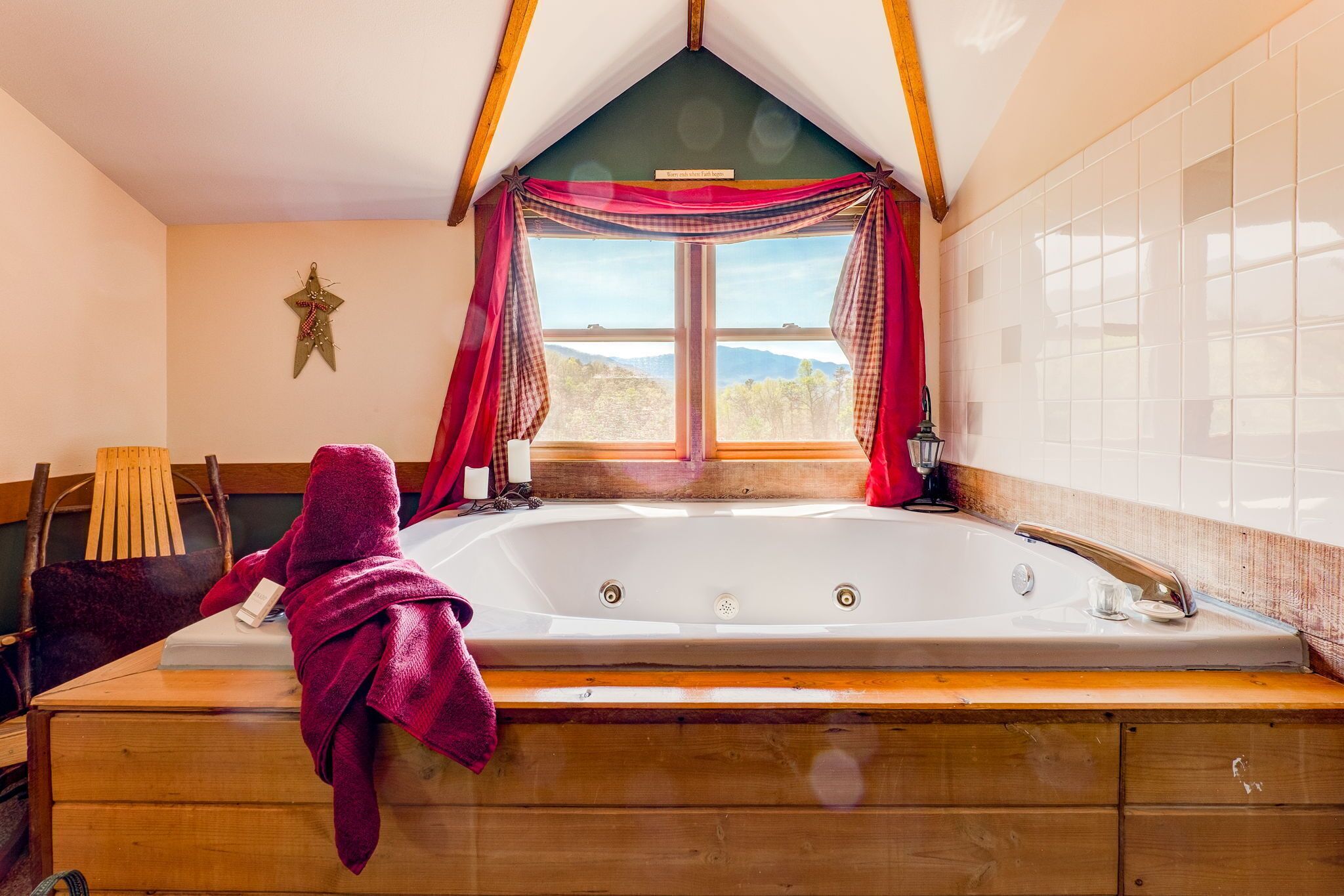 Ein Zimmer mit einer großen Badewanne, Holzmöbeln, einer Sterndekoration und einem fenster mit Vorhängen.