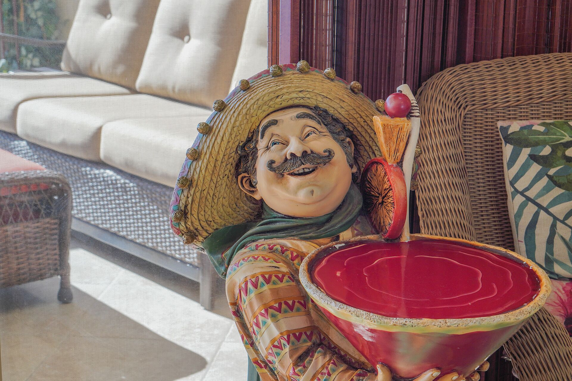 A decorative figure holding a bowl, a wicker chair, and a cushioned sofa in a well-lit room.