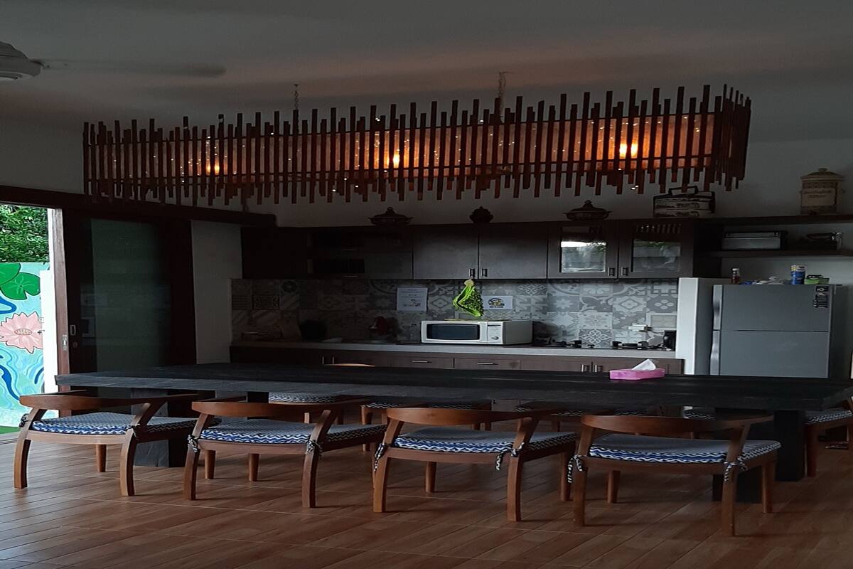 Une cuisine moderne dotée d’un îlot central, de chaises en bois et d’un luminaire suspendu.