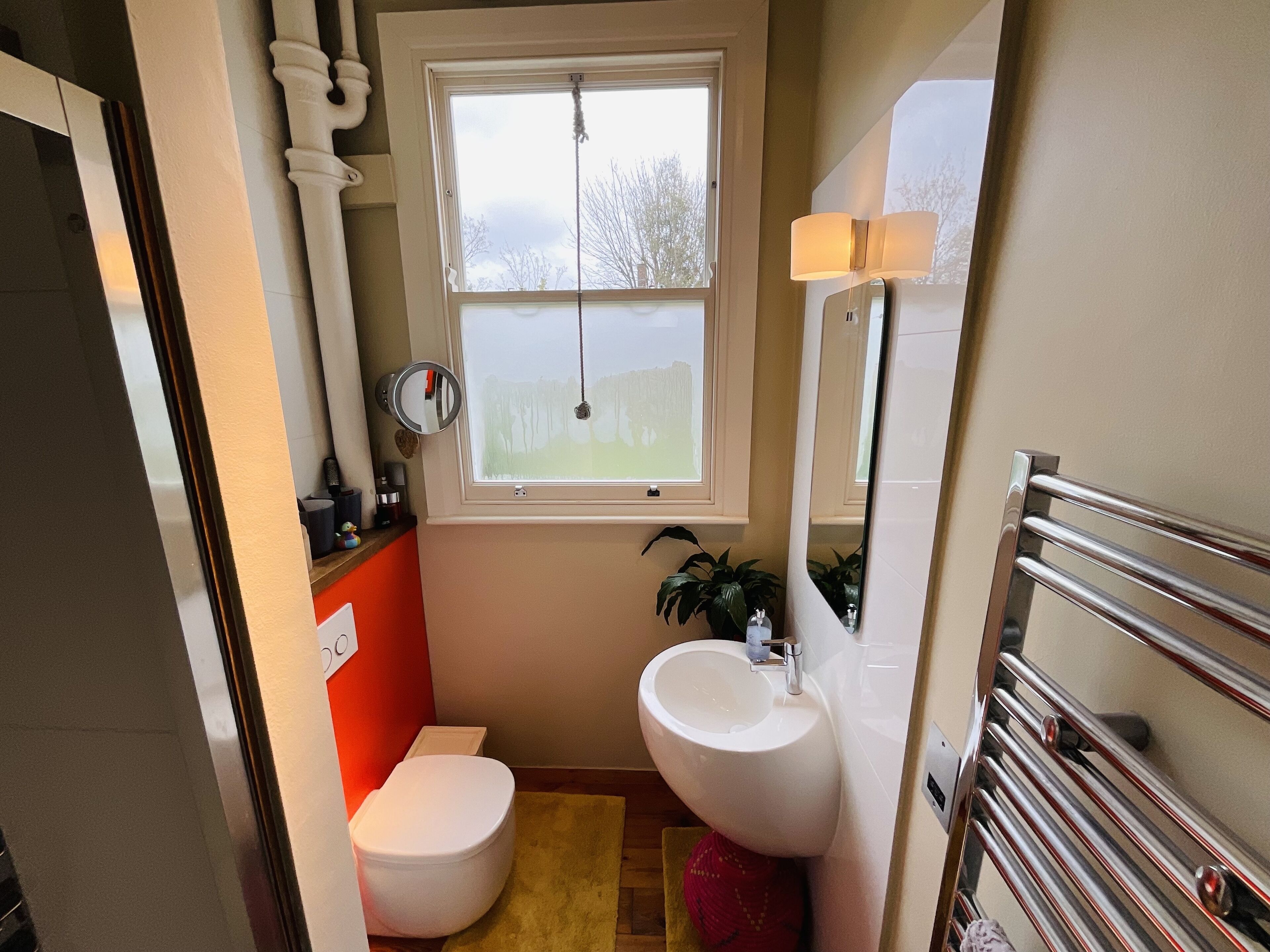 Ein kleines Badezimmer mit Toilette, Waschbecken und Fenster.