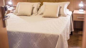 A neatly made bed with a white bedspread and pillows, a wooden headboard, and bedside lamps.