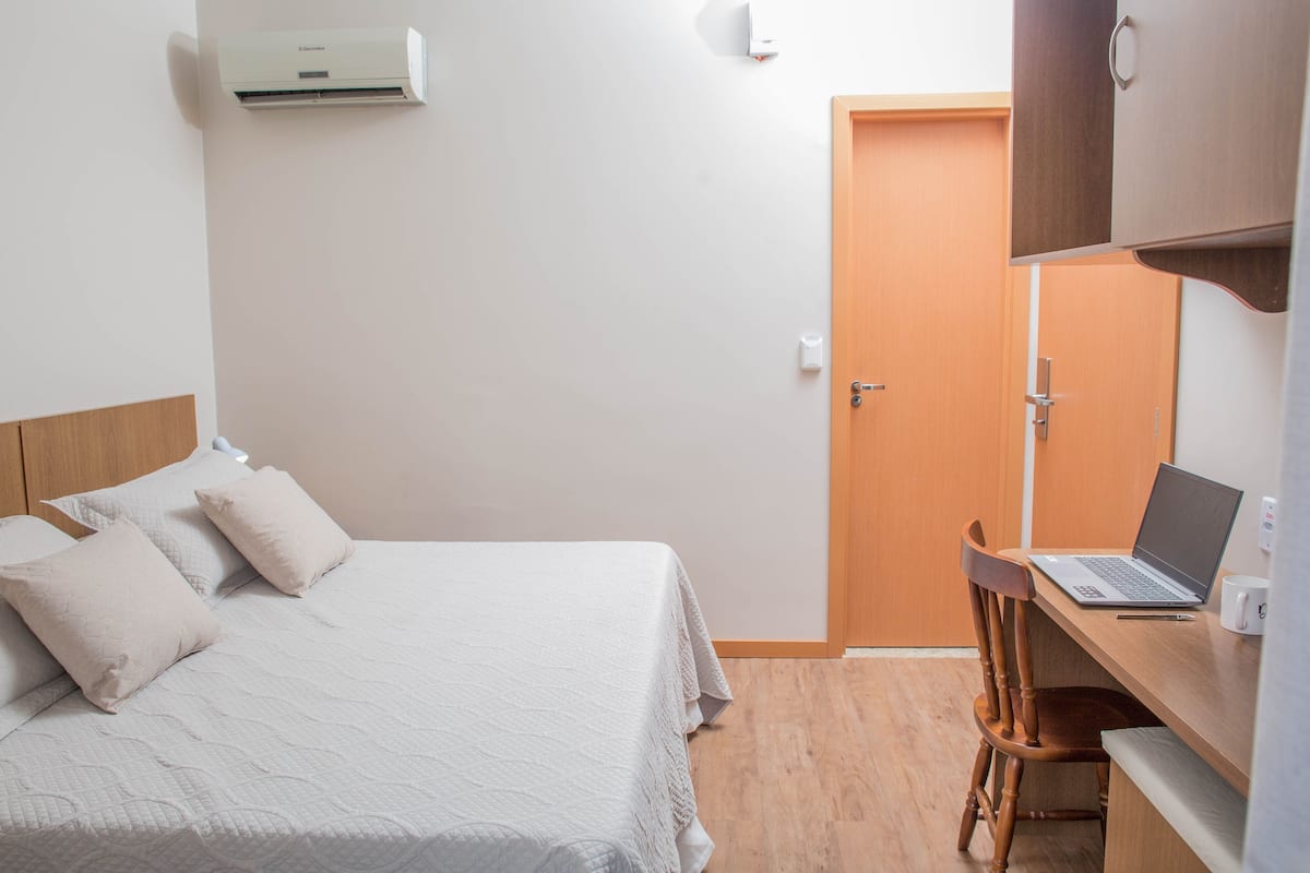 Une chambre à coucher avec un lit, un bureau avec un ordinateur portable et une armoire.