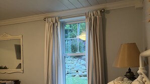 Ett sovrum med en säng, ett fönster med gardiner, en lampa och en spegel.