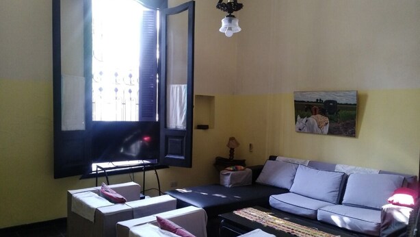 A living room with a sofa, a television, and a massage table. - FABULOSO BUENOS AIRES  ONE (Ground floor Balvanera)
