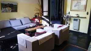 A living room with a sofa, two armchairs, a coffee table, a fan, and a painting on the wall. - FABULOSO BUENOS AIRES  ONE (Ground floor Balvanera)