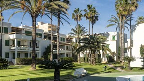 Un resort con palmeras, piscina y césped bien cuidado.