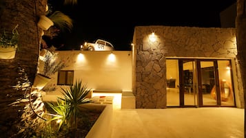 Un edificio moderno con fachada de piedra, un coche estacionado en la azotea y una entrada bien iluminada.