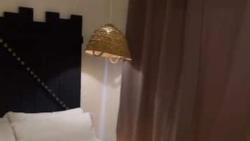 Una cama con cabecera, lámpara y cortinas.