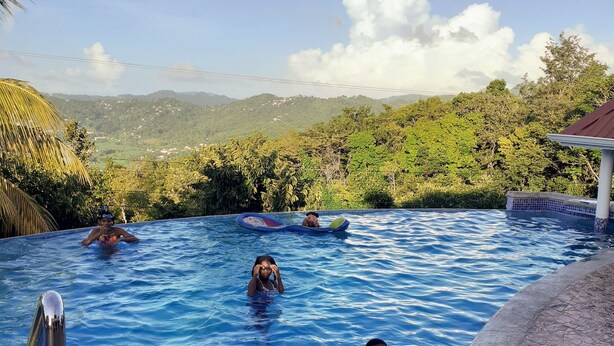 A swimming pool with clear blue water, surrounded by lush greenery and hills in the background. - Captivating Mountain Views, Ocean Views,  Romantic getaway (Anse La Raye)