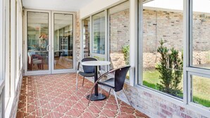 A sunlit patio with a patterned floor, a round table, and two chairs.