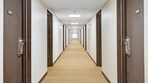 A long, narrow hotel corridor with doors numbered 224 and 225, featuring a carpeted floor and a ceiling with fluorescent lighting.