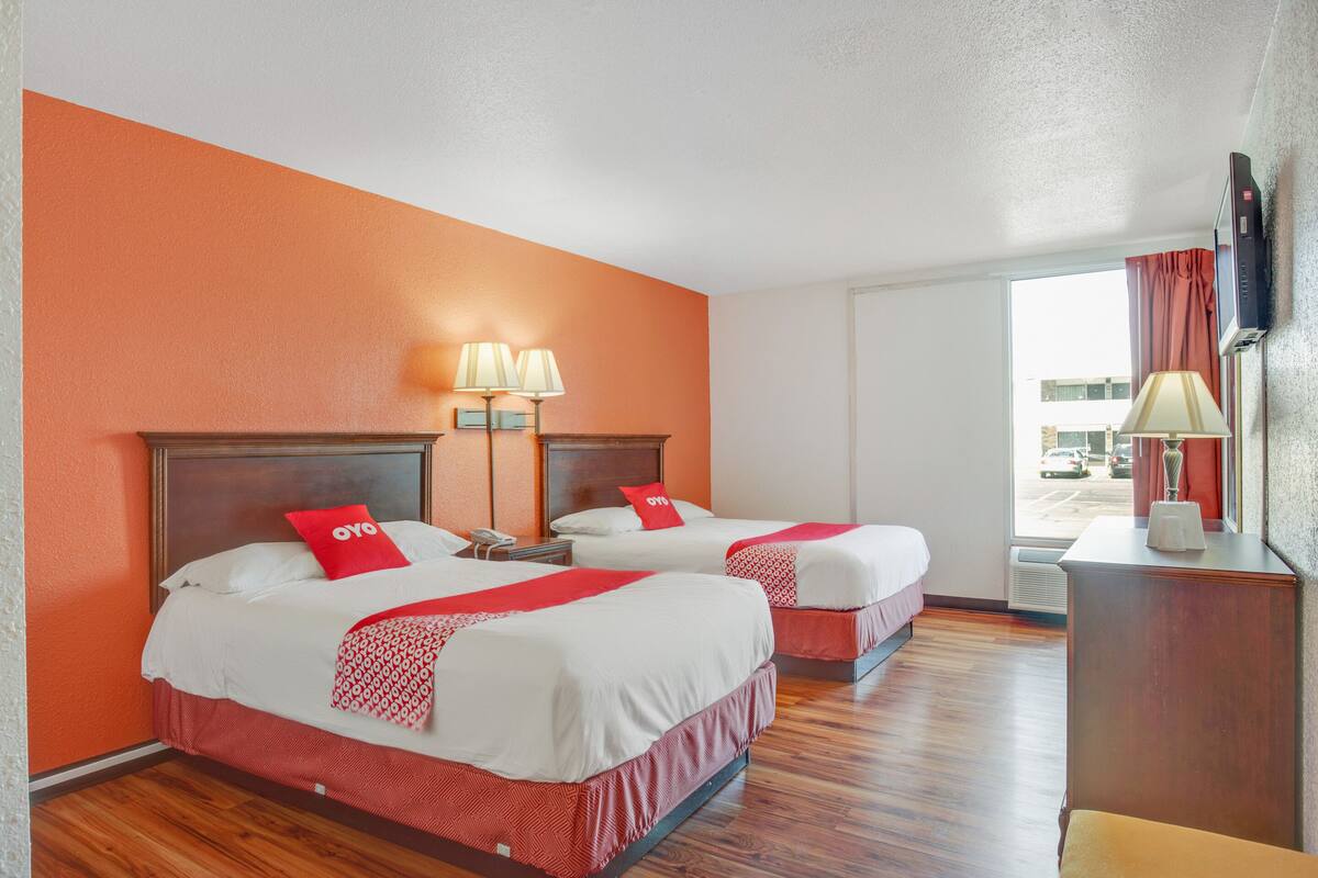 A hotel room with two beds, a desk, and a TV.