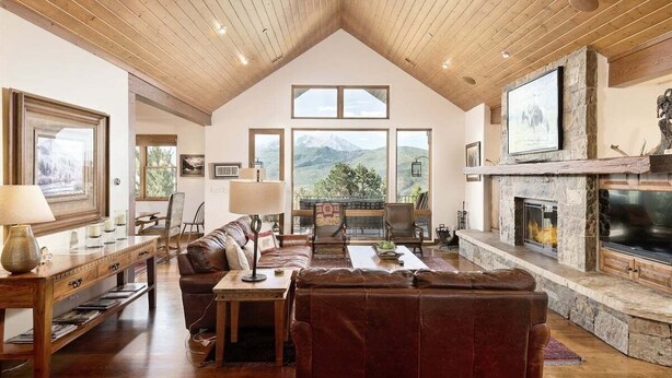 A spacious living room with a high ceiling, a fireplace, and large windows offering mountain views. - 10-Acre Mid-Valley Retreat with Hot Tub, Game Room & Sopris Views (Carbondale)