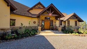 A two-story house with a stone foundation, a wooden front porch, and a gravel driveway. - 10-Acre Mid-Valley Retreat with Hot Tub, Game Room & Sopris Views (Carbondale)