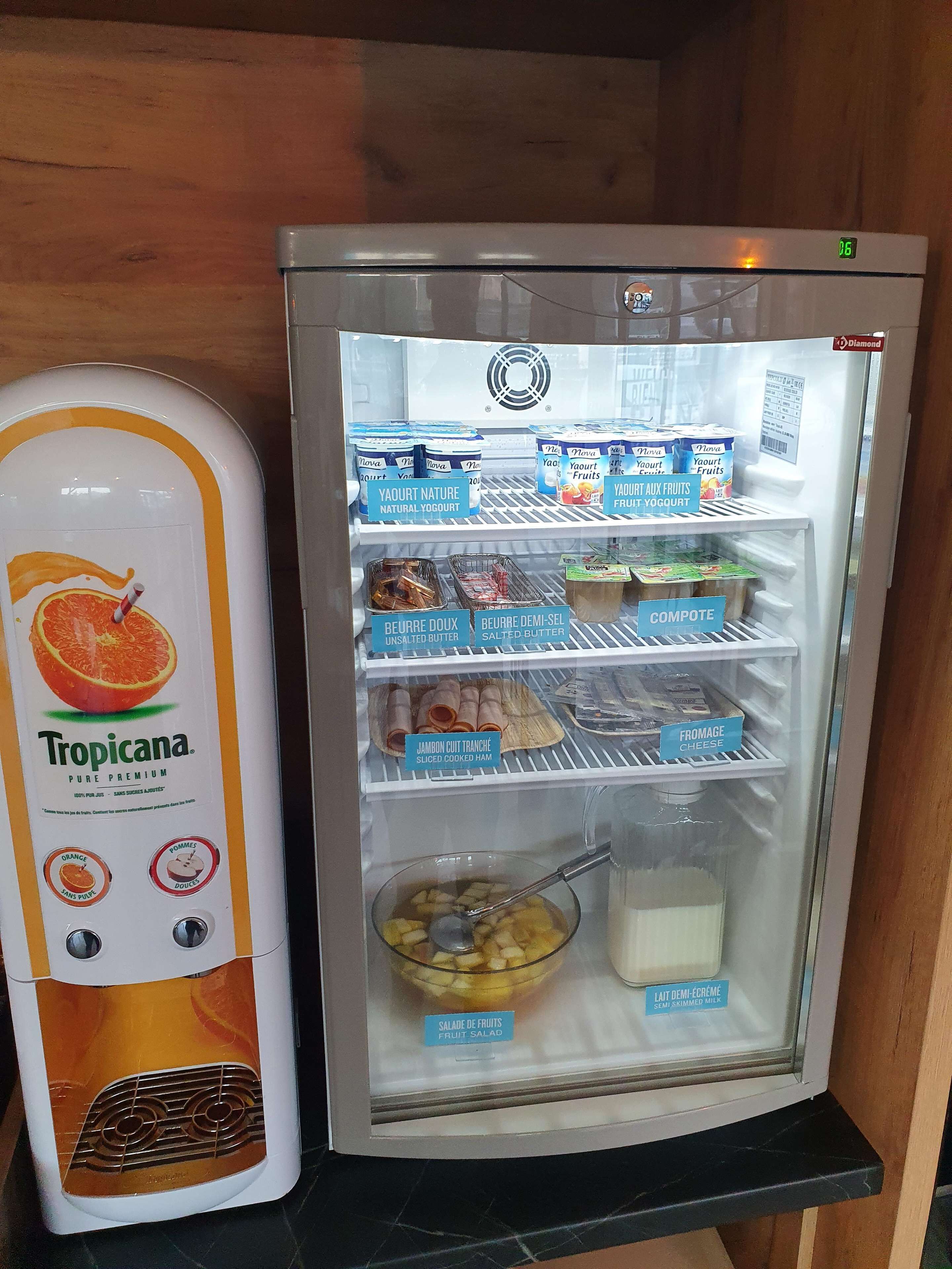 Un refrigerador lleno de diversos alimentos, incluyendo yogur natural, mantequilla sin sal y jamón cocido en rodajas.