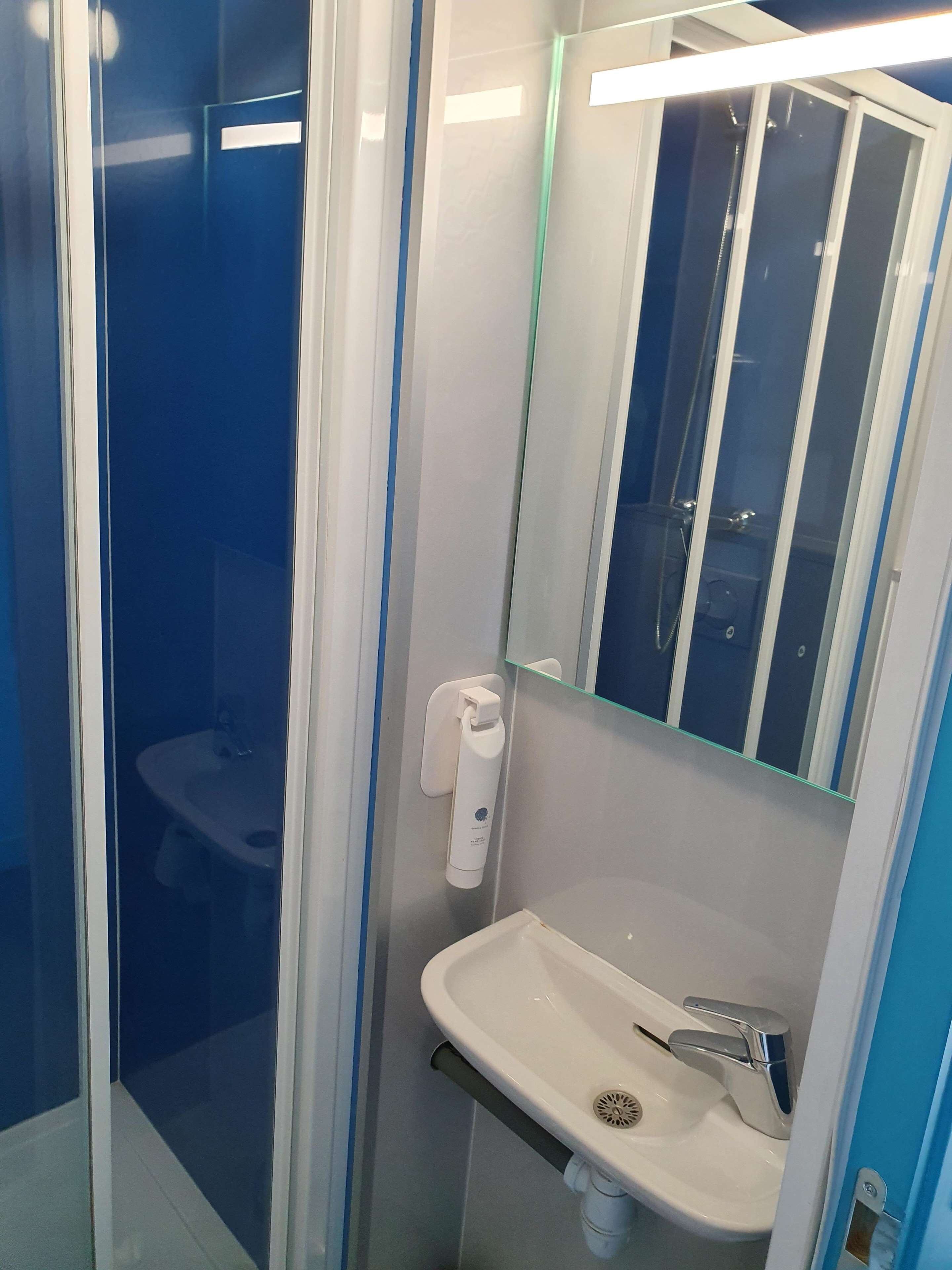 A bathroom with a glass-enclosed shower, a white sink, and a mirror above it.