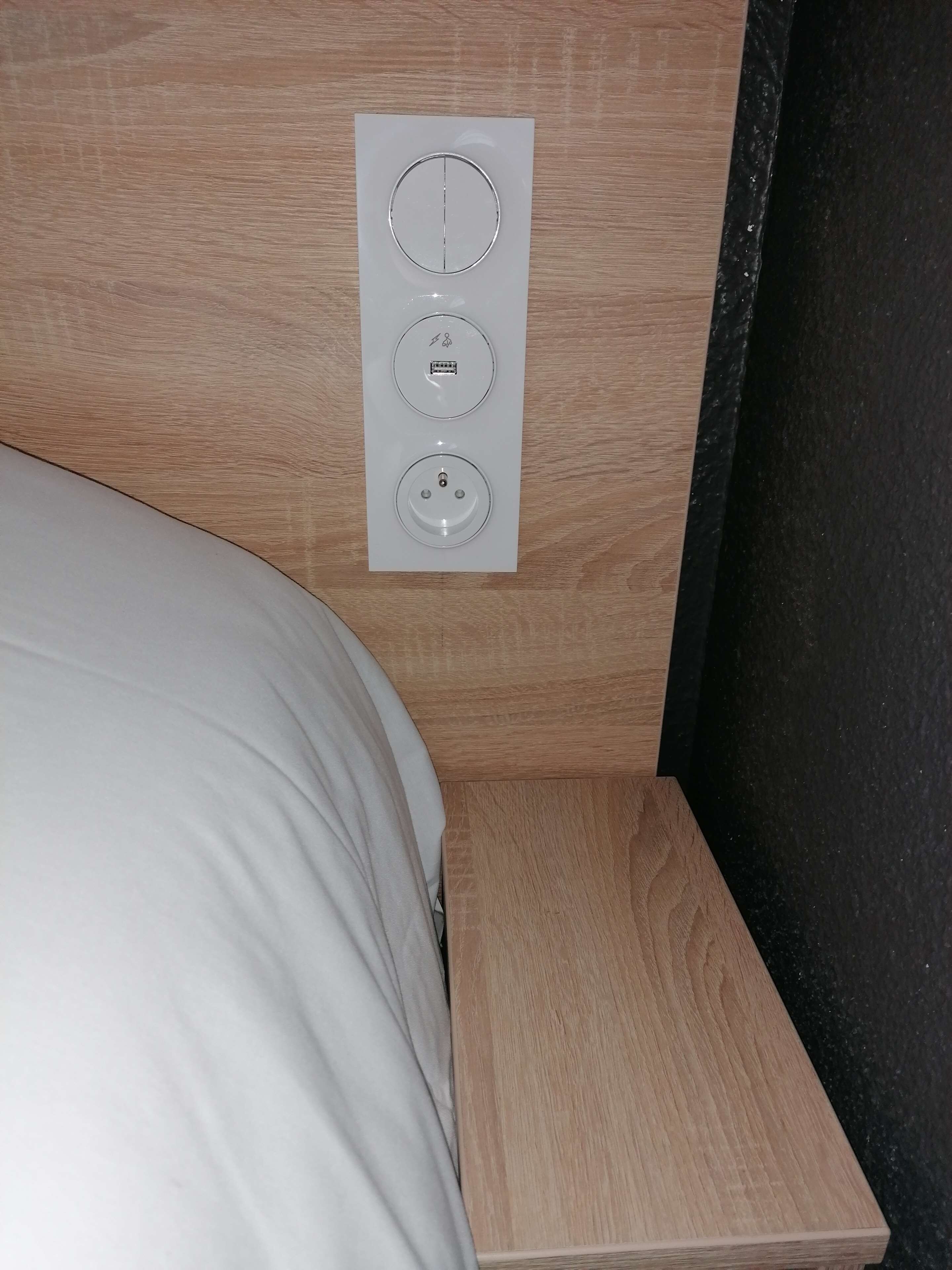 A bed with a white pillow and a wooden headboard.