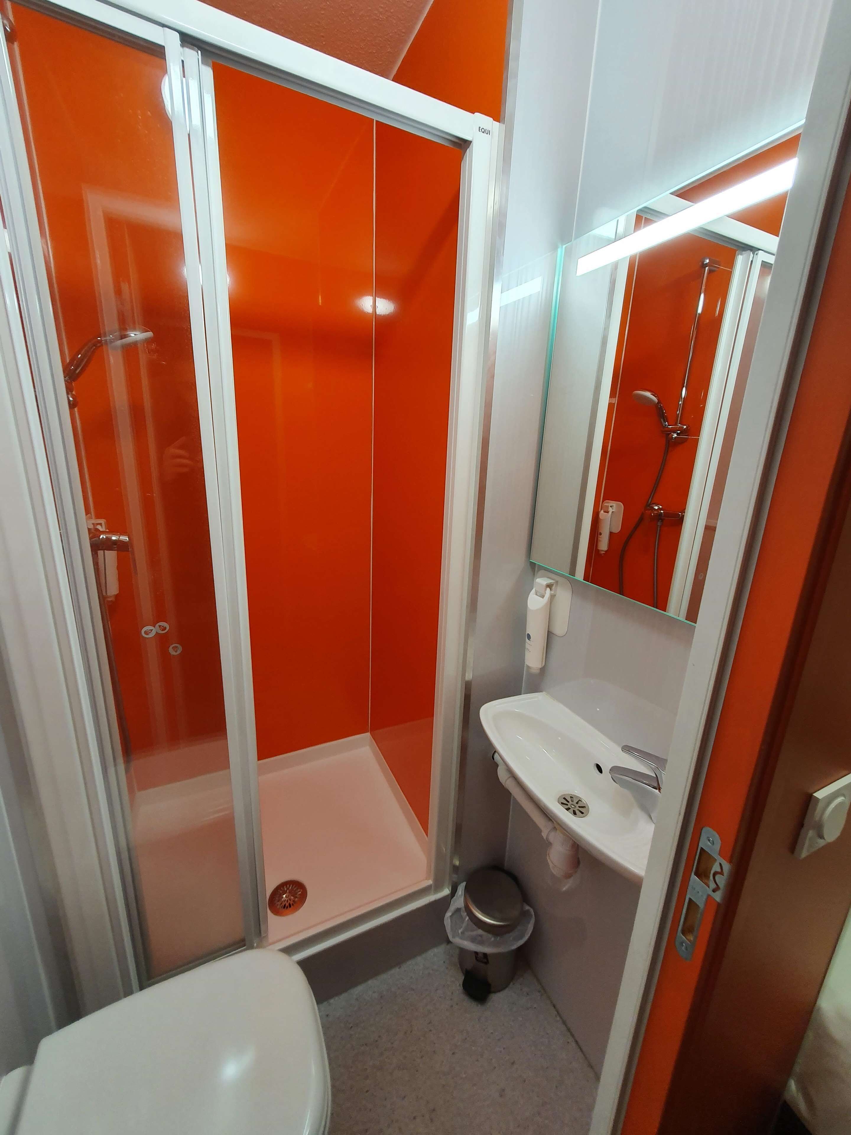 A compact bathroom with a glass-enclosed shower, a white sink, and a toilet.