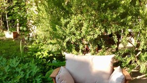 Une table en bois avec une chaise rembourrée, le tout installé dans un jardin.