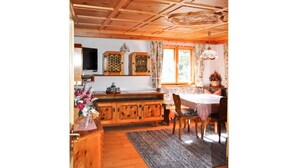 Interior de una cabaña de madera con cocina, comedor y una ventana con cortinas.