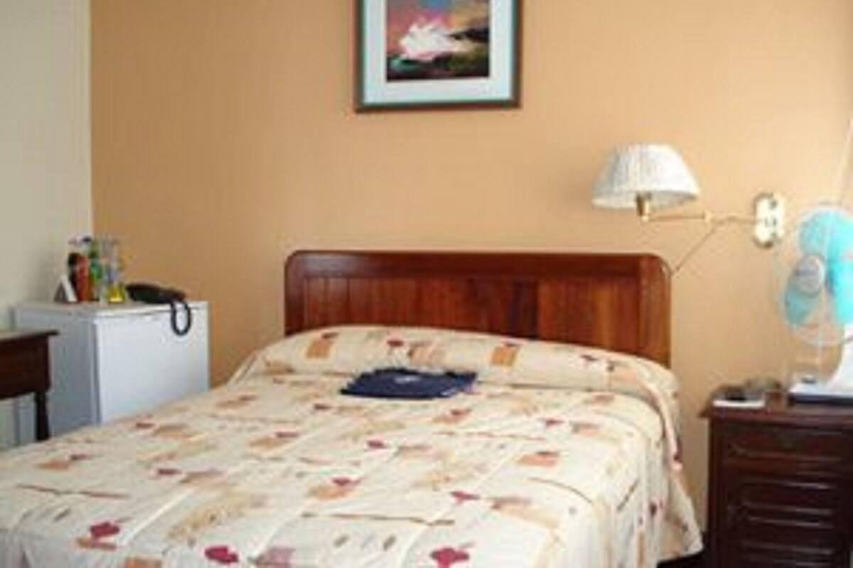 Un dormitorio con una cama de madera, una mesita de noche, una lámpara y un escritorio pequeño con otra lámpara.