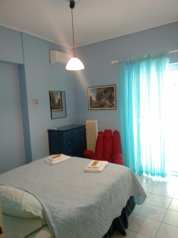 A bedroom with a bed, a blue dresser, a radiator, and a window with curtains. - Palinas comfy home!! (Kalamata)