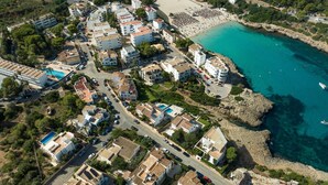 An aerial view of a coastal residential area with houses, a beach, and a rocky shoreline.