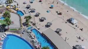 Un complexe hôtelier doté de plusieurs piscines, de zones de plage et de parasols.