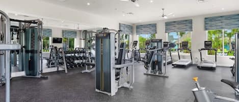 Une salle de sport équipée de divers appareils d’exercice, notamment des tapis de course, des appareils de musculation et des poids libres.