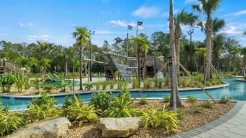 A pool area with palm trees, a wooden bridge, and a clear sky.