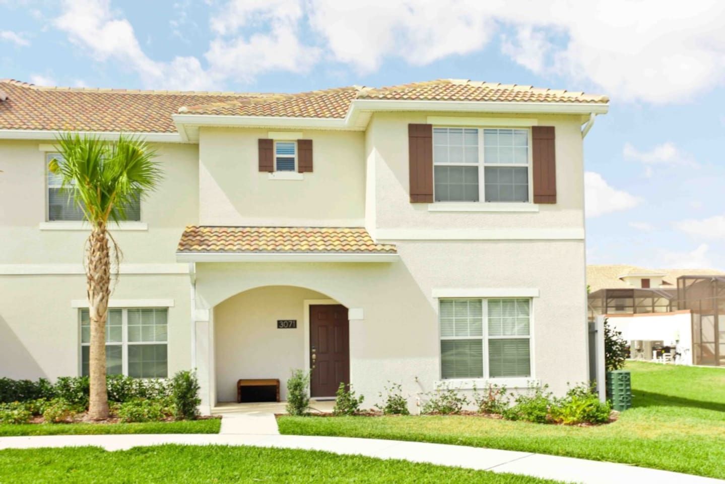 Una casa de dos pisos con techo de tejas, entrada principal con puerta y un porche pequeño.